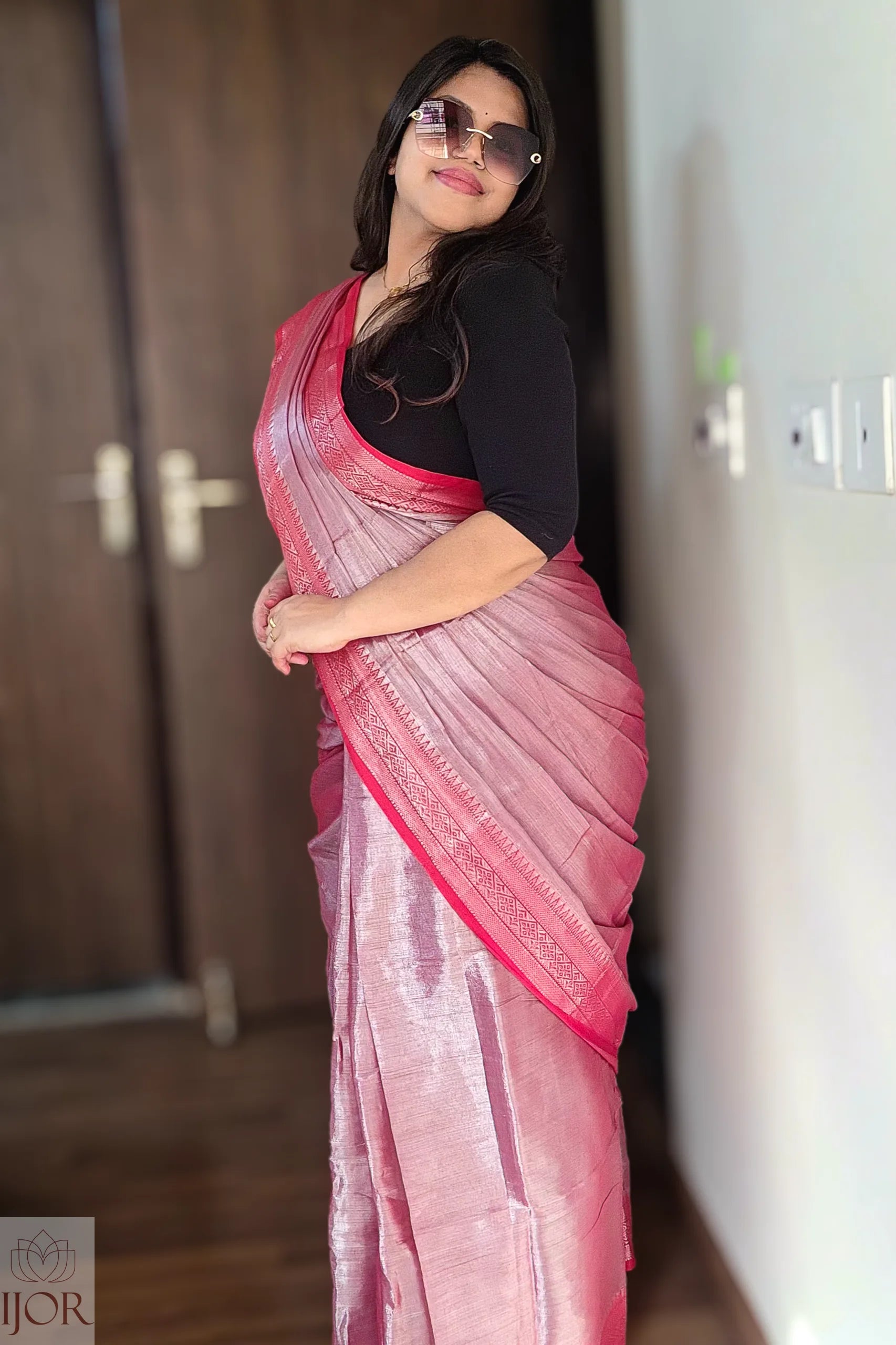Woman wearing a Lavender Pure Tissue Cotton Saree with Rich Red Border with a black blouse indoors.