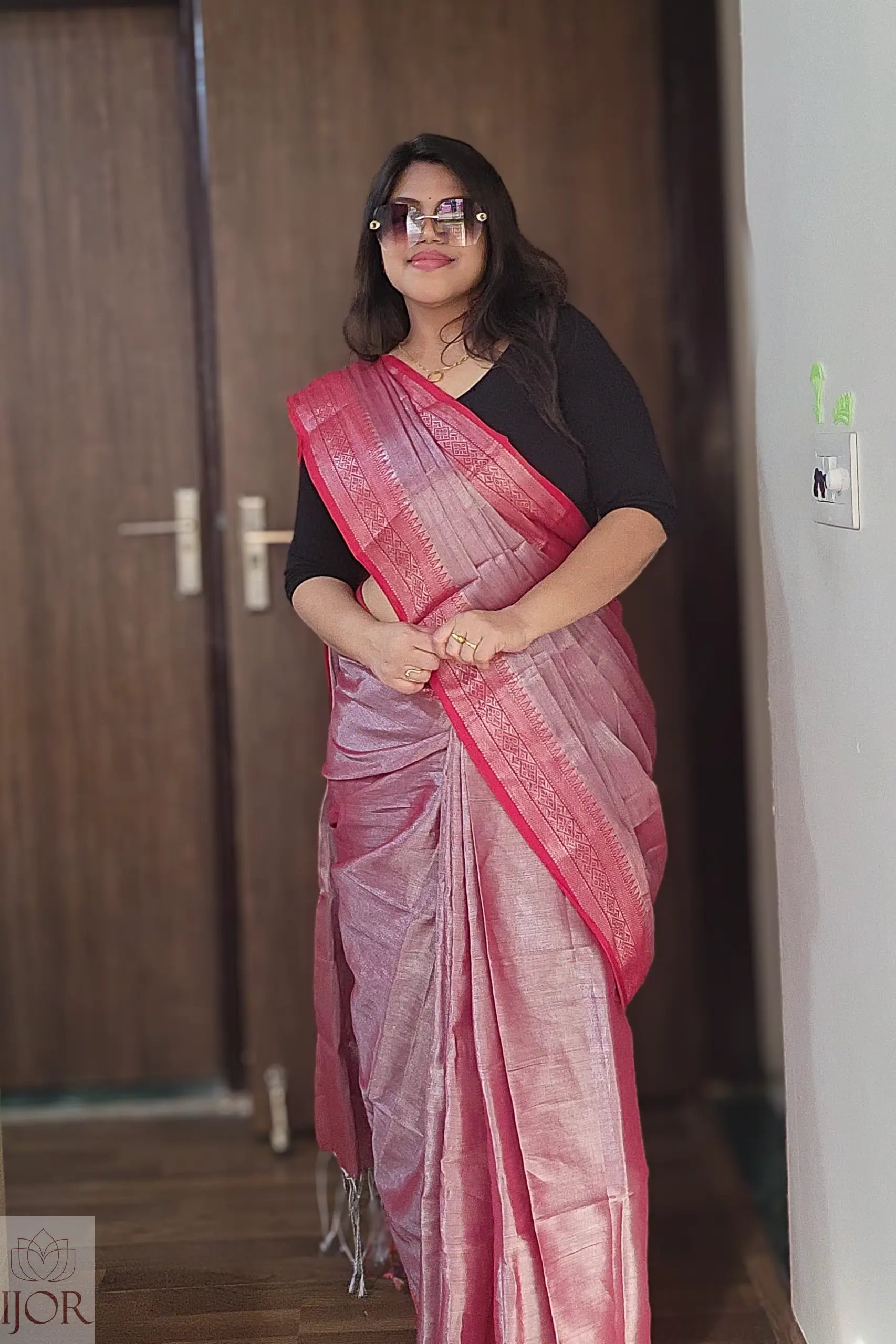 Woman wearing a Lavender Pure Tissue Cotton Saree with Rich Red Border with a black blouse indoors.