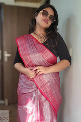 Woman wearing a Lavender Pure Tissue Cotton Saree with Rich Red Border with a black blouse against a neutral wall.