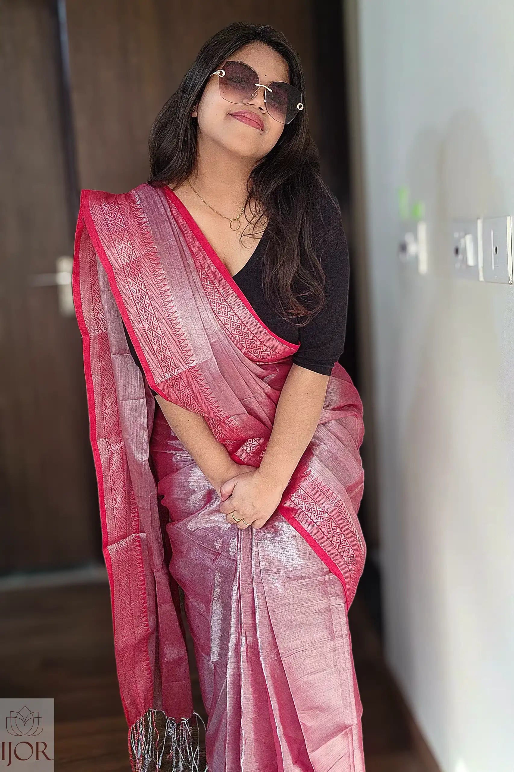 Woman wearing a Lavender Pure Tissue Cotton Saree with Rich Red Border with a black blouse indoors.