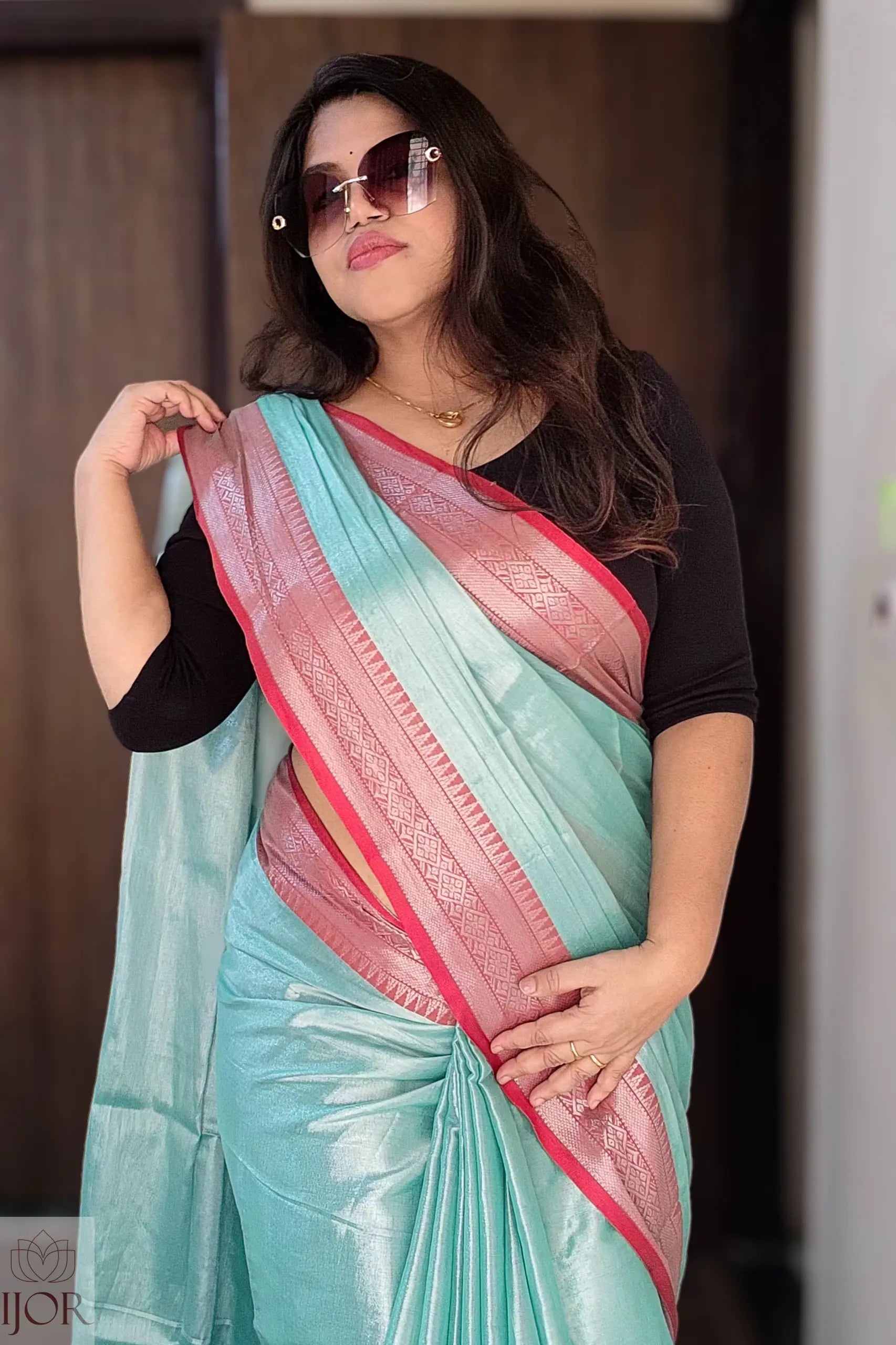 Woman wearing a Turquoise Blue Pure Tissue Cotton Saree with Rich Red Border and sunglasses.
