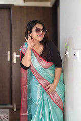 Woman wearing a Turquoise Blue Pure Tissue Cotton Saree with Rich Red Border indoors.