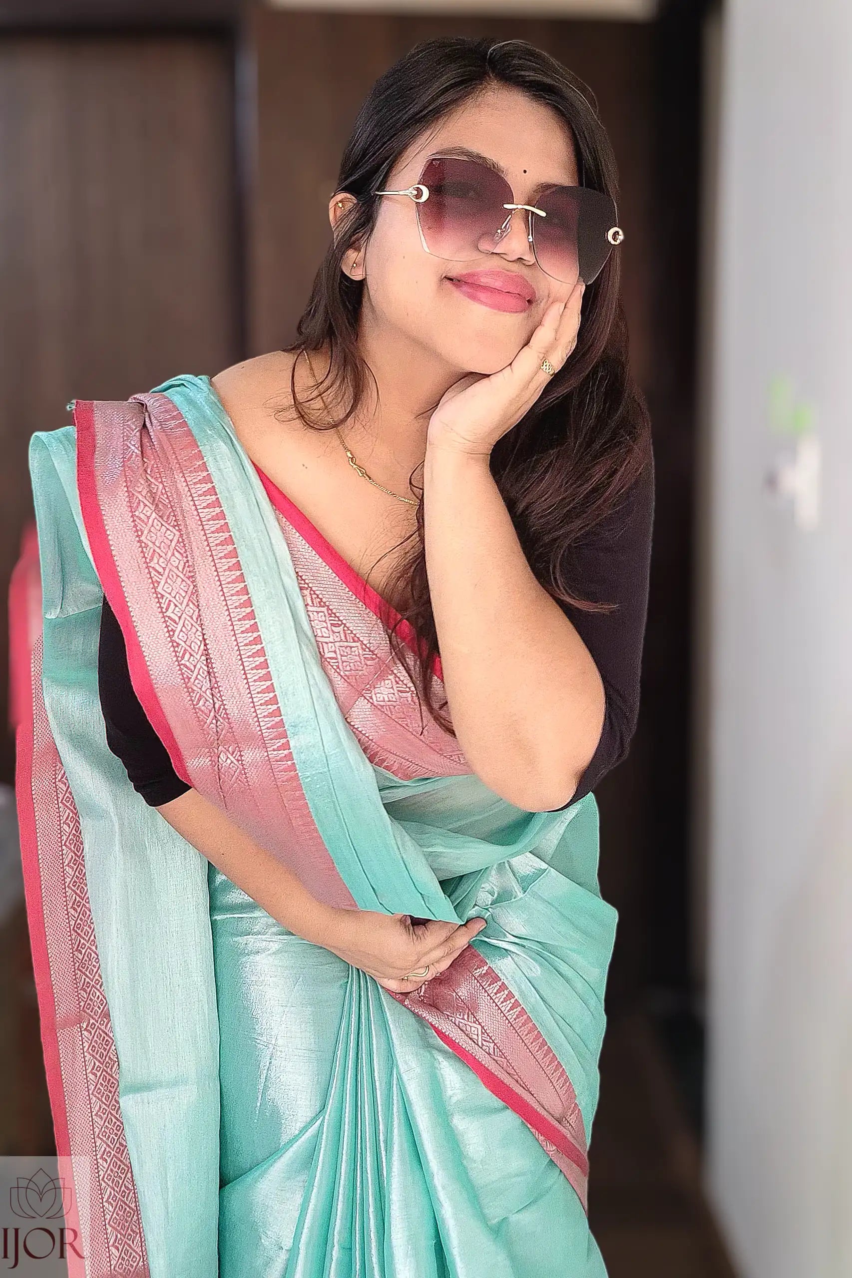 Woman wearing a Turquoise Blue Pure Tissue Cotton Saree with Rich Red Border with pink border, posing indoors.