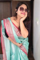 Woman wearing a Turquoise Blue Pure Tissue Cotton Saree with Rich Red Border with pink border, posing indoors.