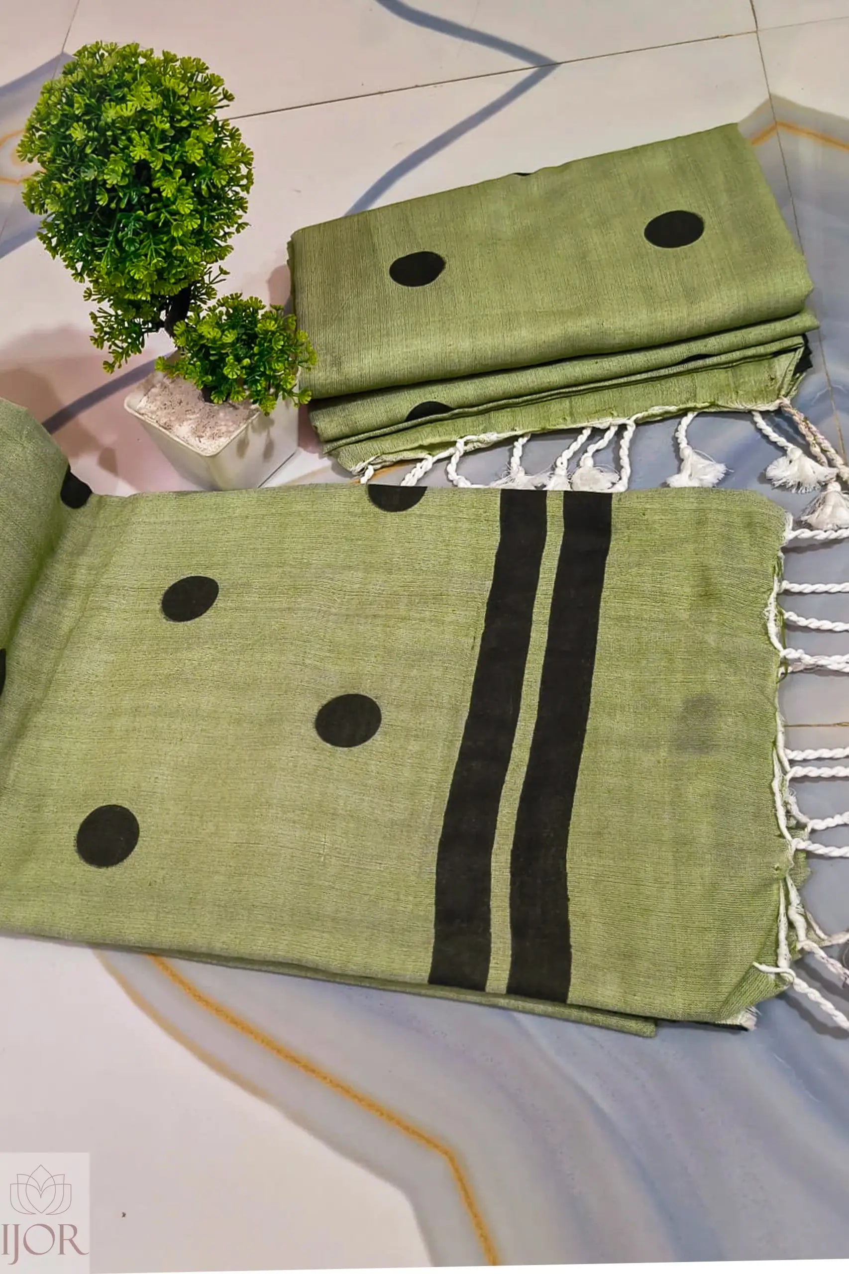 Pure Khadi Cotton Olive Green Saree with black polka and beautiful white tassels on a tiled floor.
