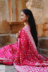 Nandini Yallareddy in Banarasi Soft Georgette Silk Red Saree with silver booti work showing anchal and border of saree is sitting on stone steps.