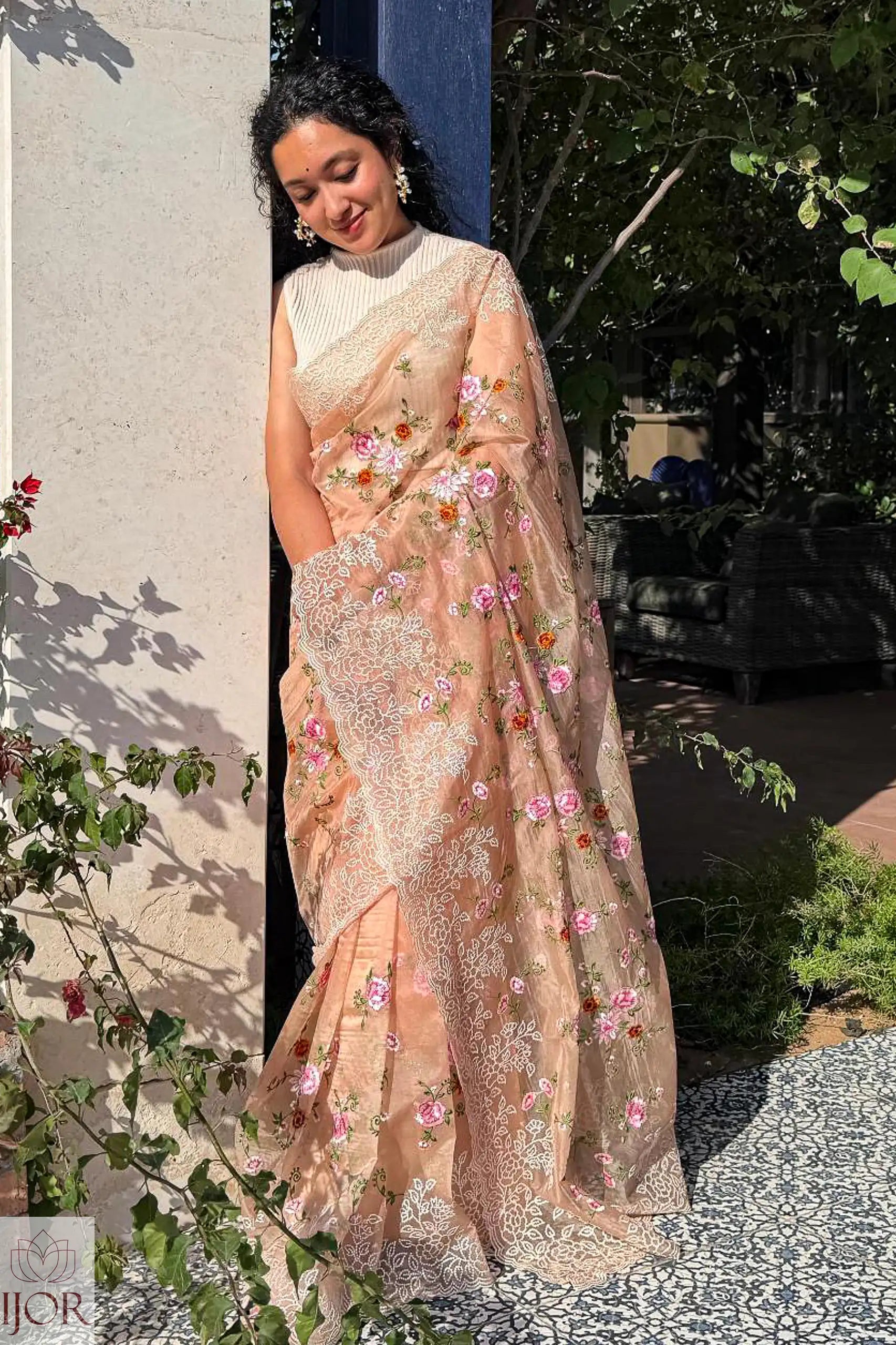 Gana Murali in a traditional Banarasi Soft Organza Silk Saree Golden standing outdoors under the sun kissed light.