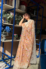 Gana Murali in a traditional Banarasi Soft Organza Silk Saree Golden standing under the sun shade among planters.