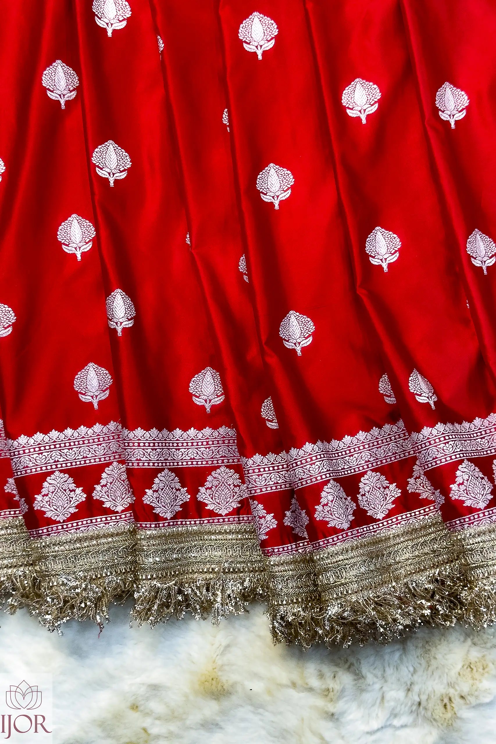 Red Mashru Silk Saree with Maharani Lace patterns and gold lace on a textured surface