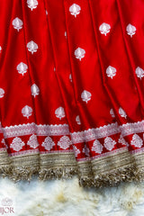 Red Mashru Silk Saree with Maharani Lace patterns and gold lace on a textured surface