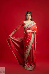 Woman wearing a Red Mashru Silk Saree with Maharani Lace on a red background