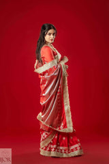 Woman wearing a Red Mashru Silk Saree with Maharani Lace against a red background