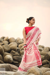 Woman in a Dhonkhali Red and White Pure Cotton Check saree standing among rocks with a blurred background