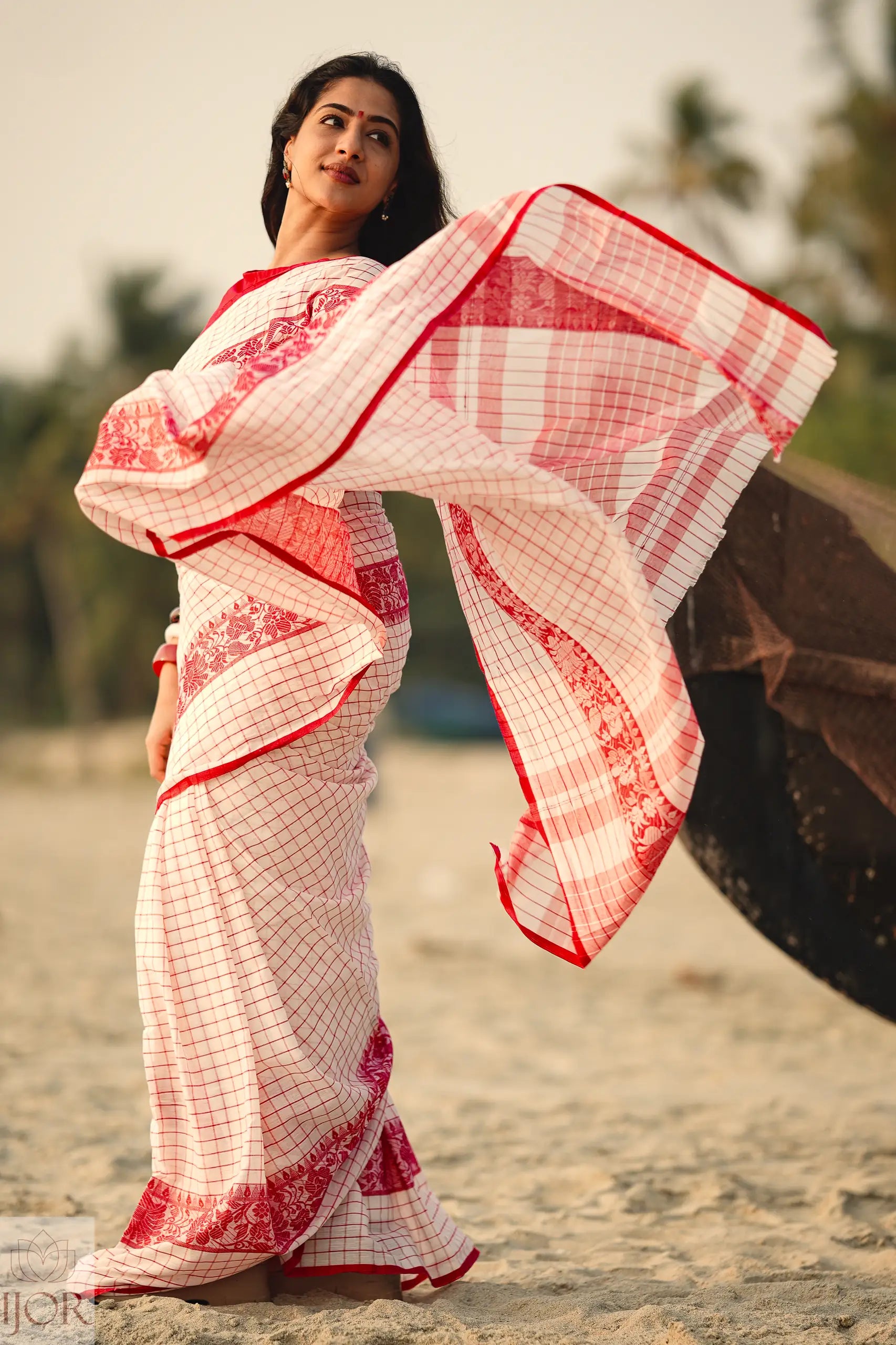 Woman wearing a Dhonkhali Red and White Pure Cotton Check saree with a blurred background