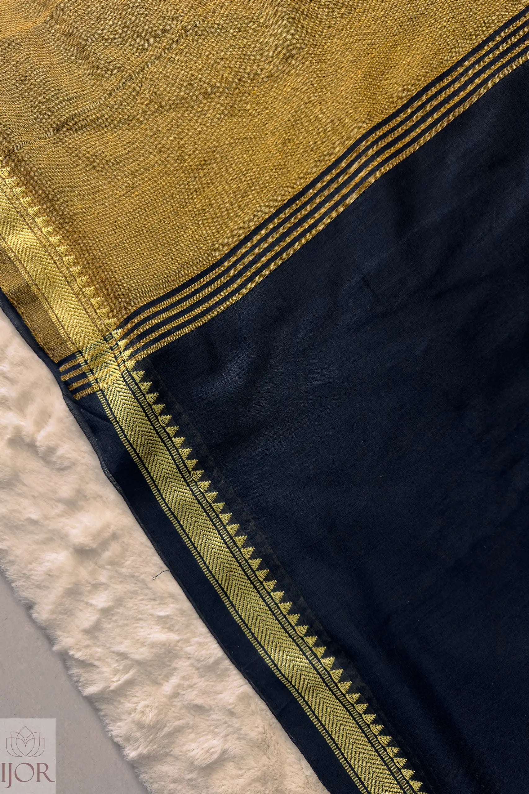 Close-up of a Pure Cotton Saree Black and Yellow border on a textured surface