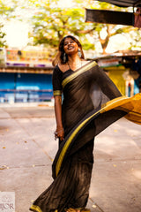 Divya Darshini ft in Jharokha Pure Cotton Saree Black and Yellow with gold temple border standing outdoors.