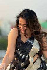 Kavya wearing a Kora Orgenza Silk Black Saree sitting outdoors with a blurred background