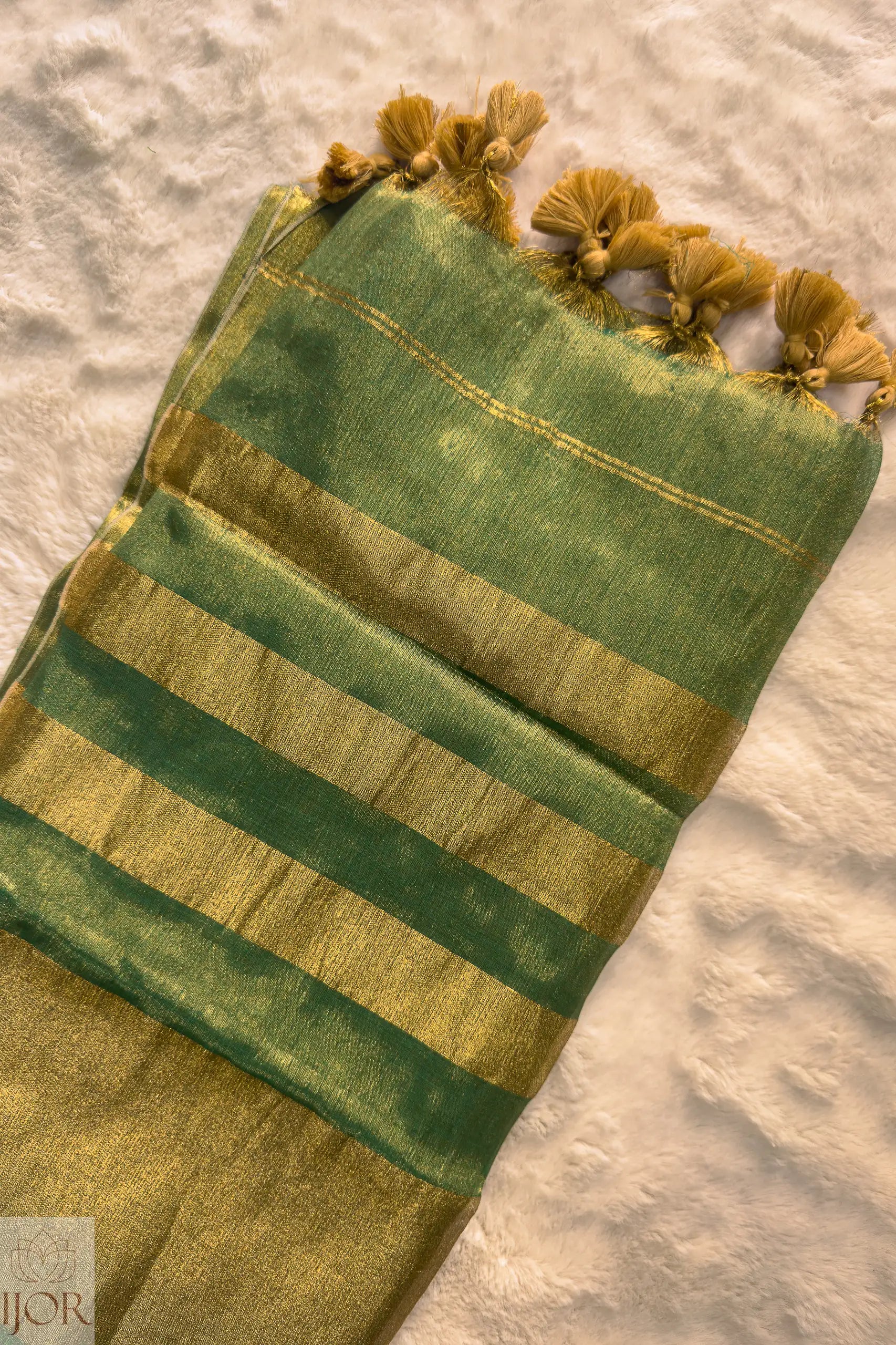 Green Golden Zari Pure Tissue Cotton Saree tassels on a textured surface