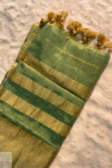 Green Golden Zari Pure Tissue Cotton Saree tassels on a textured surface