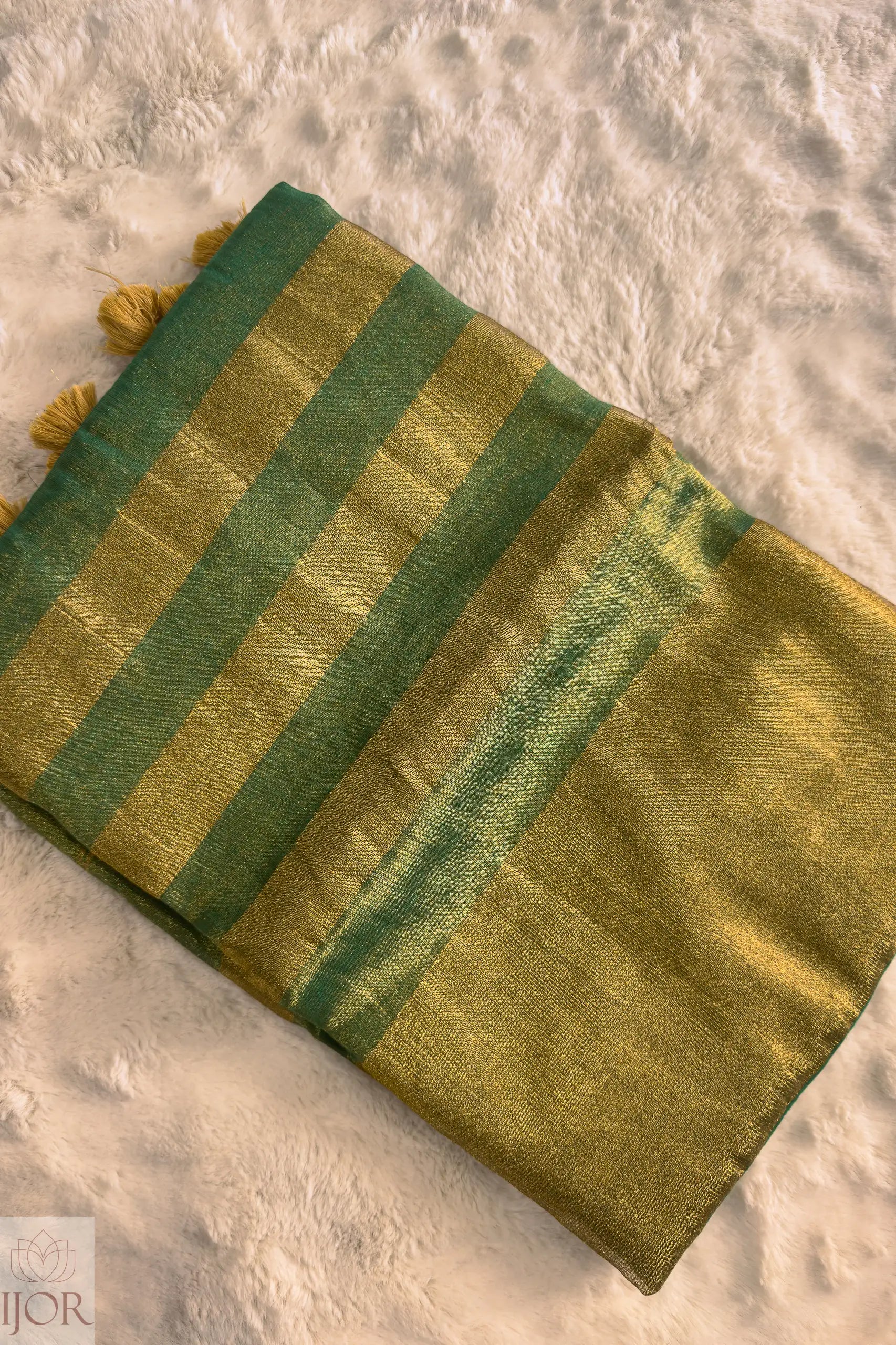 Green Golden Zari Pure Tissue Cotton Saree with tassels on a textured beige background