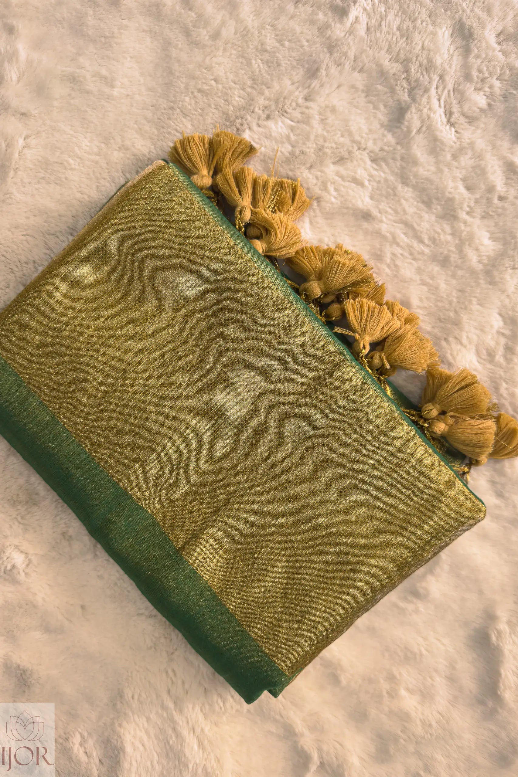 Green Golden Zari Pure Tissue Cotton Saree with yellow tassels on a textured surface