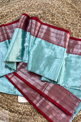 Turquoise Blue Pure Tissue Cotton Saree with Rich Red Border with red border on a textured surface