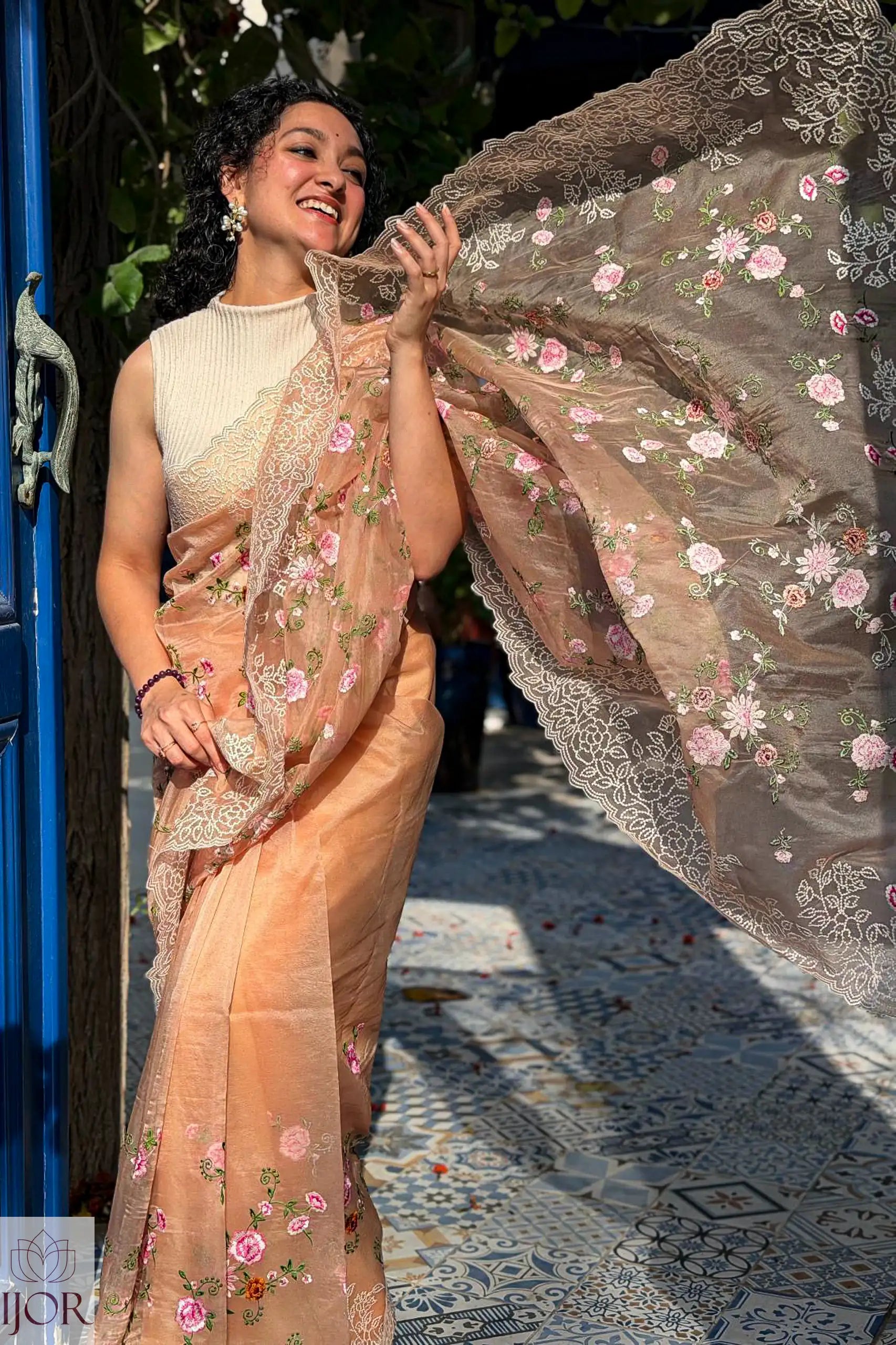 Gana Murali in a traditional Banarasi Soft Organza Silk Saree Golden with floral patterns, standing outdoors.