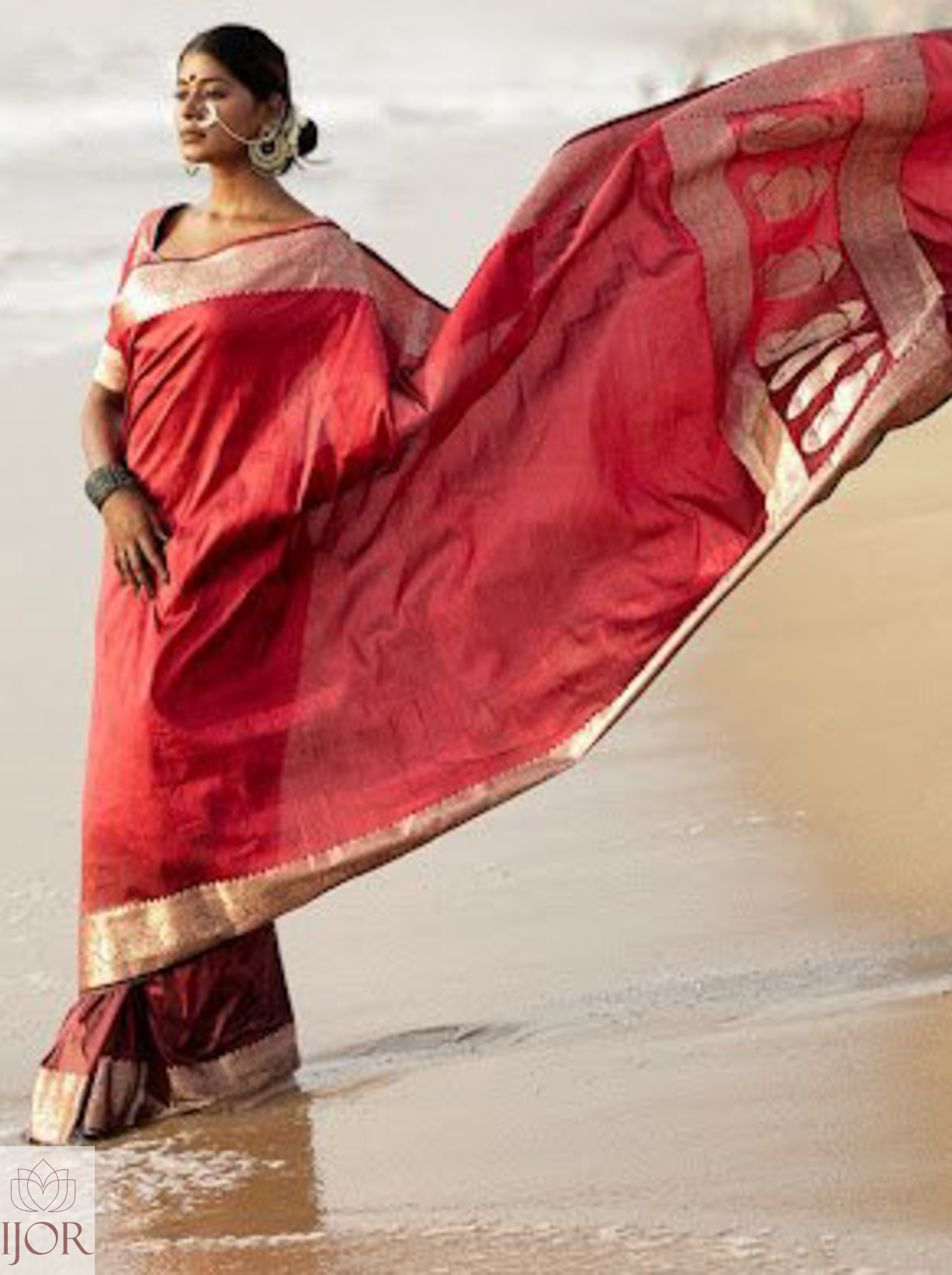 Divya Darshini ft. in Banarasi Soft Semi Katan Silk Saree Red with silver zari border and pallu standing on a beach.