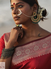 Divya Darshini wearing traditional jewelry and a Banarasi Soft Semi Katan Silk Saree Red with a blurred background