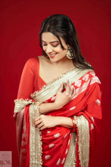Woman in a Red Mashru Silk Saree with Maharani Lace against a red background