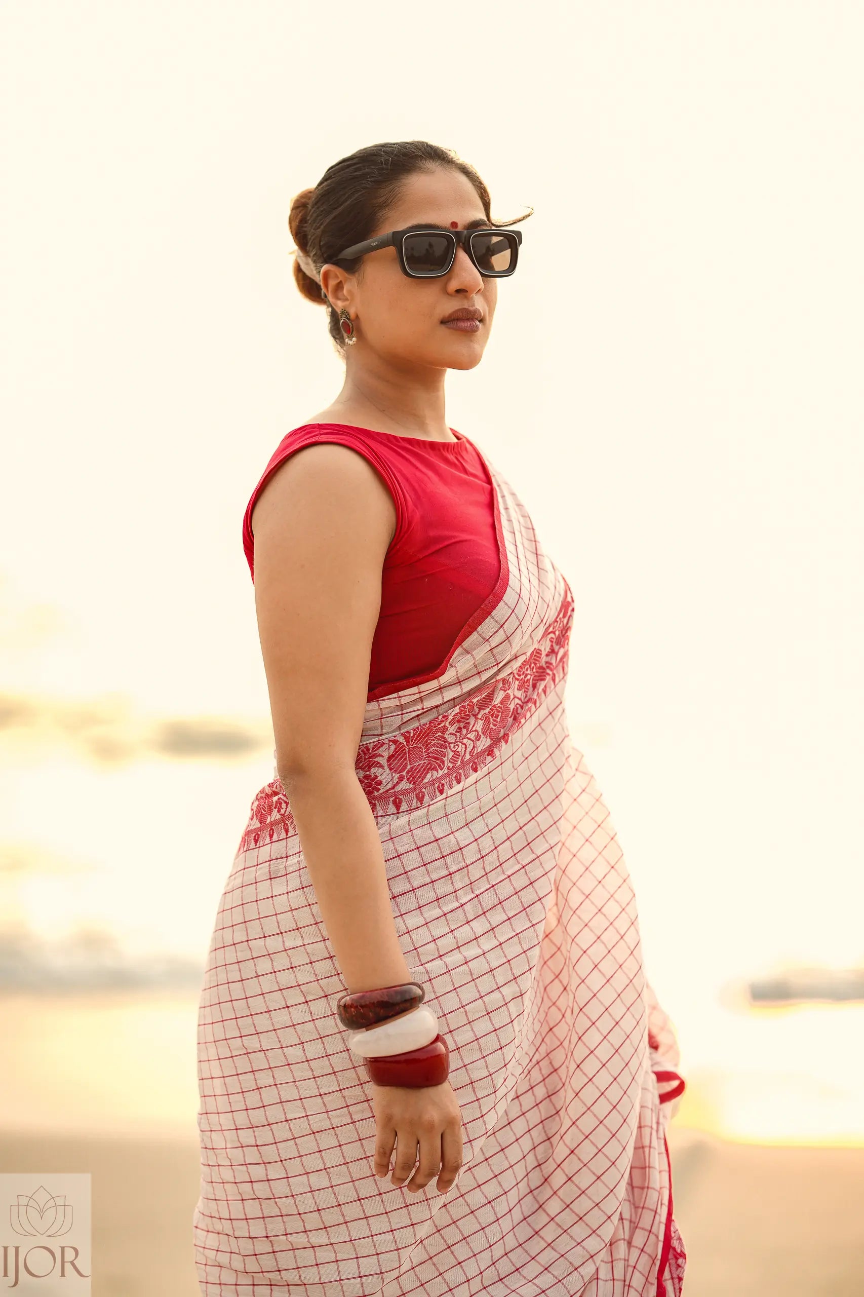 Woman wearing a Dhonkhali Red and White Pure Cotton Check saree with a blurred background