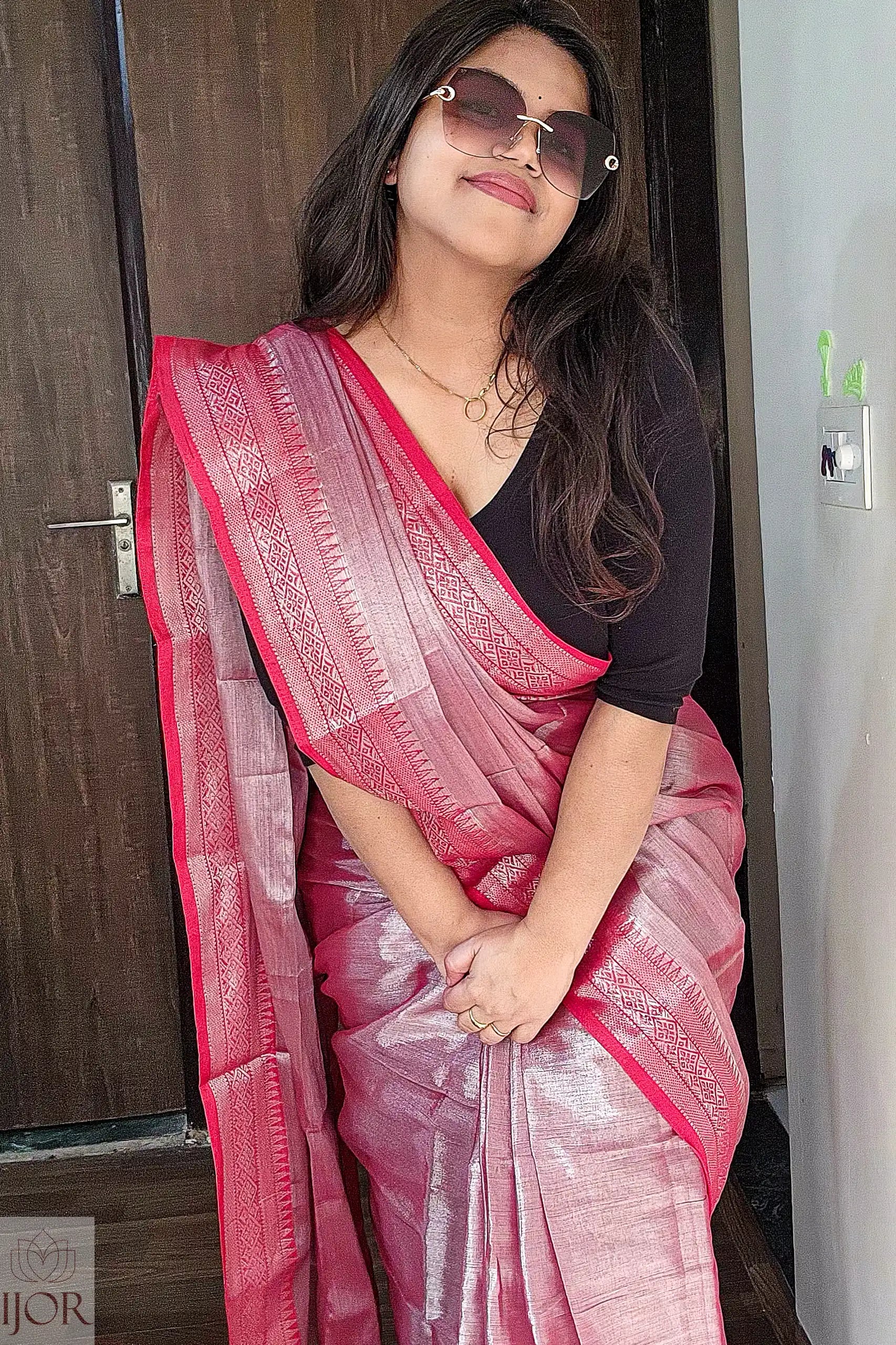 Lavender Color Pure Tissue Cotton Saree with Rich Red Border with a black blouse indoors.