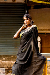 Divya Darshini ft in Jharokha Pure Cotton Saree Black and Yellow with gold temple border sitting on a bench.