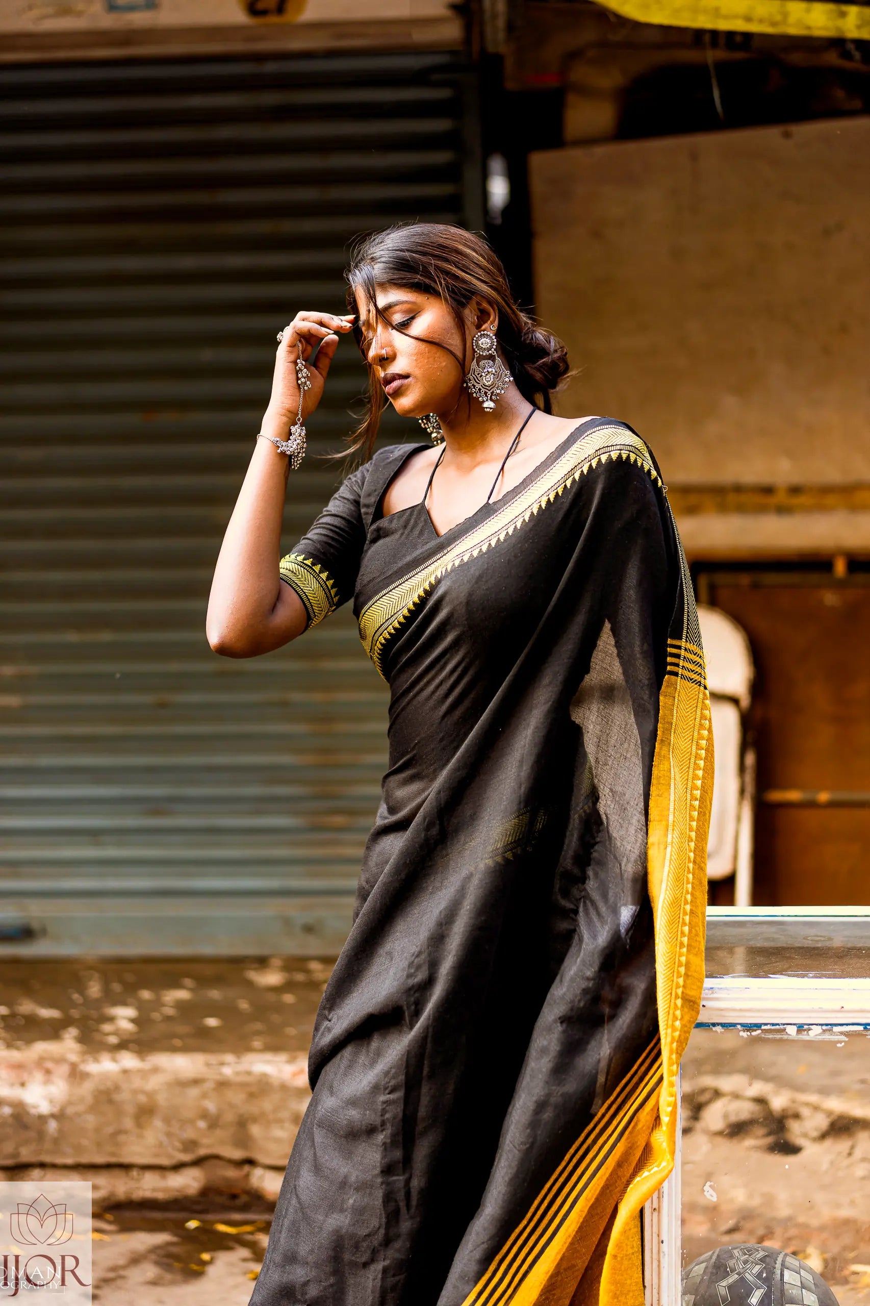 Divya Darshini ft in Jharokha Pure Cotton Saree Black and Yellow with gold temple border standing outdoors.
