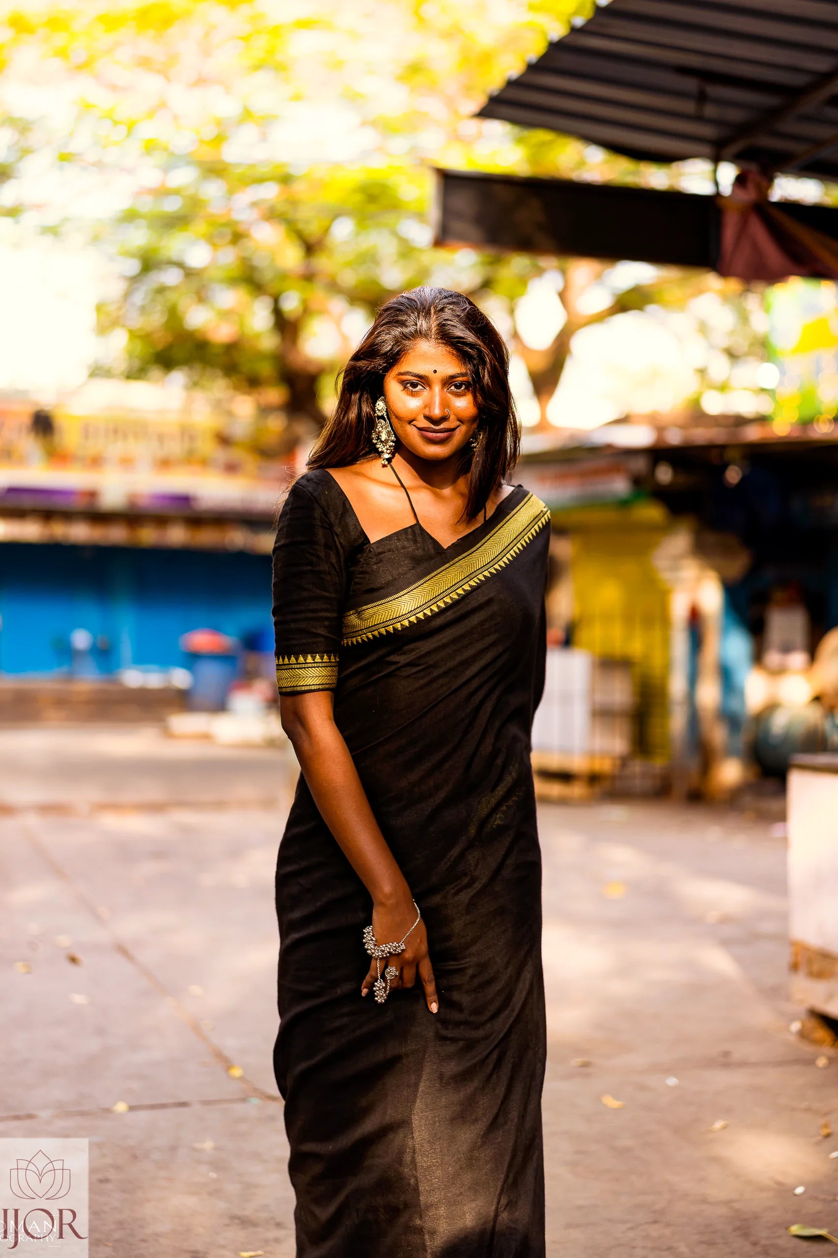 Divya Darshini ft in Jharokha Pure Cotton Saree Black and Yellow  with gold  temple border standing outdoors.