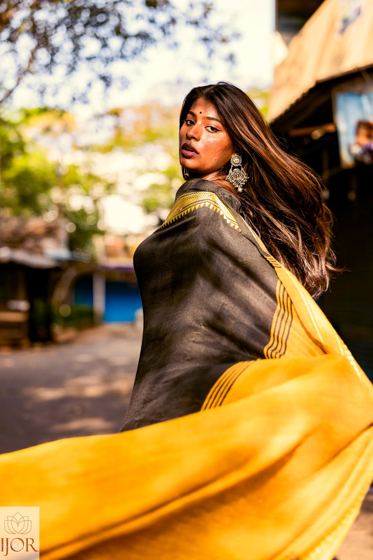 Divya Darshini ft. in Jharokha Pure Cotton Saree Black and Yellow with a blurred outdoor background