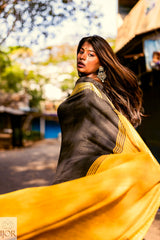 Divya Darshini ft. in Jharokha Pure Cotton Saree Black and Yellow with a blurred outdoor background