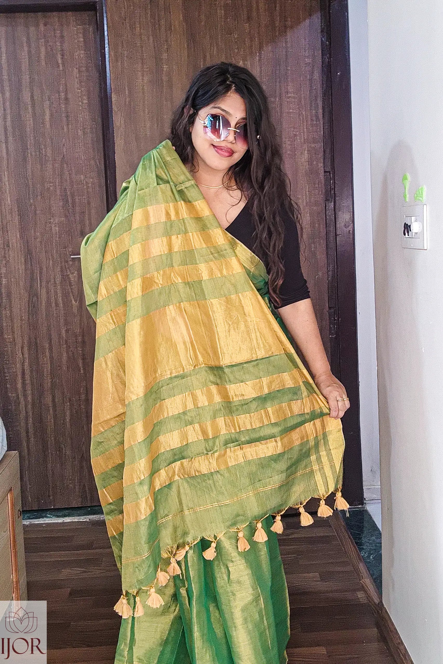   Aarti in Green Golden Zari Pure Tissue Cotton Saree with tassels indoors.