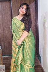   Aarti in Green Golden Zari Pure Tissue Cotton Saree with a black blouse standing indoors.