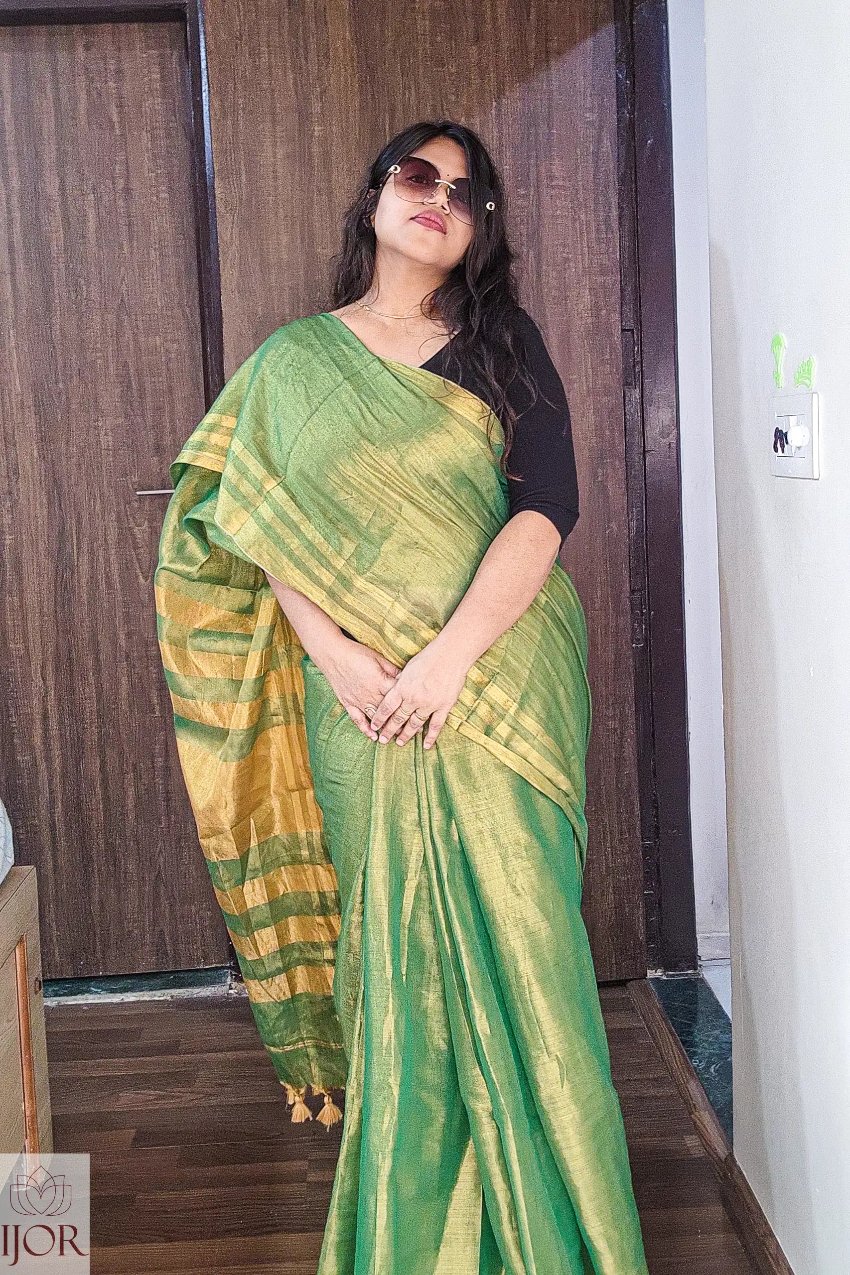   Aarti in Green Golden Zari Pure Tissue Cotton Saree with a black blouse indoors.