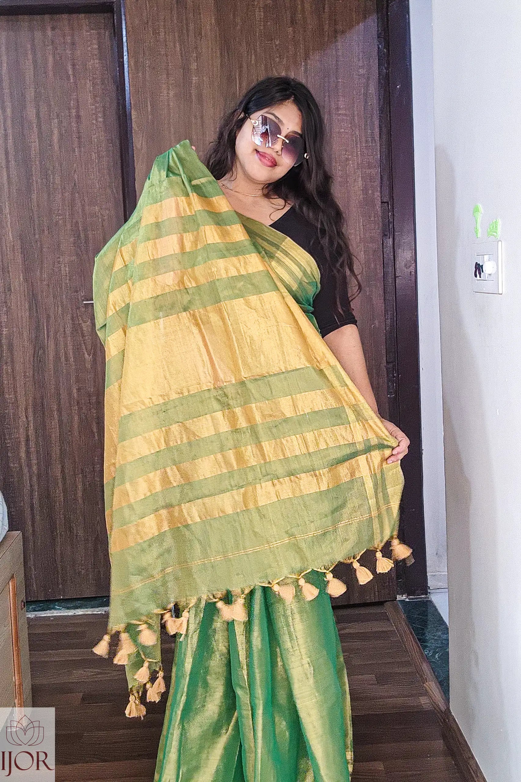   Aarti in Green Golden Zari Pure Tissue Cotton Saree with tassels indoors.