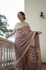 Woman wearing a Banarasi Soft Georgette Silk Brown Saree standing on a balcony.